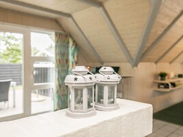 A room with a white ceiling, a window with curtains, and two white lanterns on a white ledge.