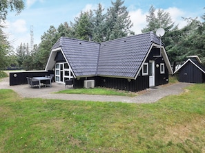 A modern house with a sloped roof, a satellite dish, and a patio with a table and chairs. - 8 Person Holiday Home in Blavand (Blavand)