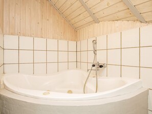 A large, freestanding bathtub in a room with tiled walls and a wooden ceiling. - 8 Person Holiday Home in Blavand (Blavand)