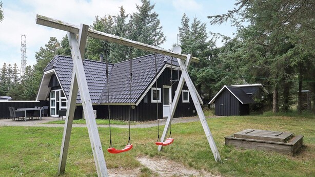 A wooden swing set in a grassy yard with a house in the background. - 8 Person Holiday Home in Blavand (Blavand)