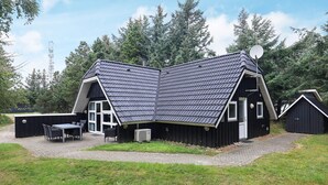 A modern house with a sloped roof, a satellite dish, and a patio with a table and chairs. - 8 Person Holiday Home in Blavand (Blavand)