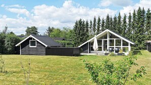 Ett modernt hus med en stor veranda och ett takförsett utomhusområde.