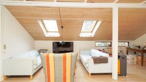 A spacious living area with two sofas, a striped armchair, and a high ceiling with skylights. - 8 Person Holiday Home in Kirke Hyllinge (Kirke Hyllinge)