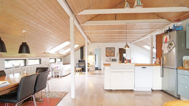 A spacious kitchen with a central island, wooden ceiling, and a dining area with a red rug. - 8 Person Holiday Home in Kirke Hyllinge (Kirke Hyllinge)