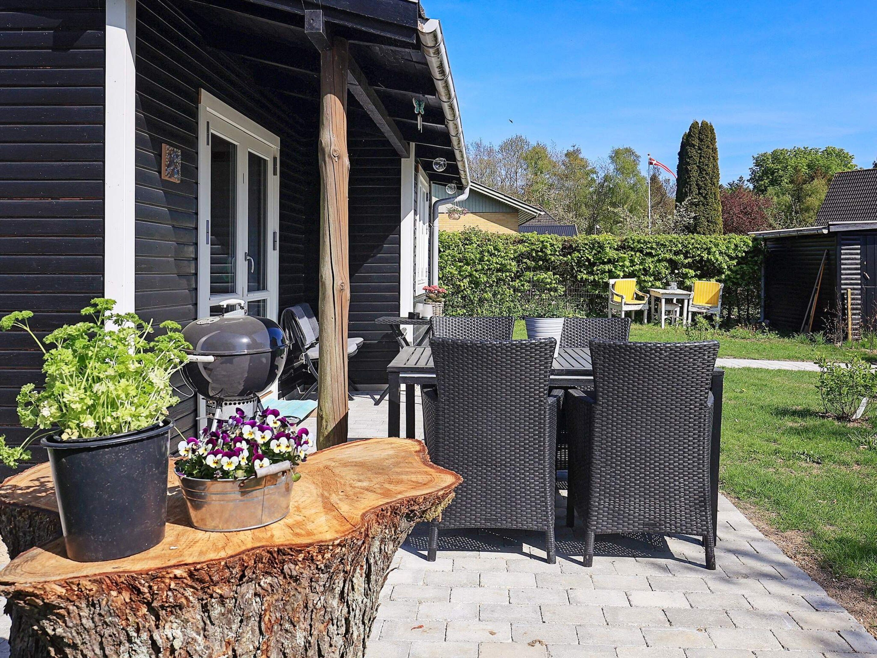A patio with wicker furniture, a grill, and potted plants.