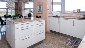 A modern kitchen with white cabinets, a granite countertop, and a window overlooking a scenic landscape. - 4 Person Holiday Home in Henne (Henne)