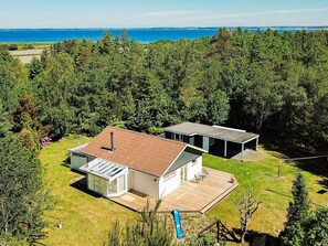 A modern house with a large deck, a glass conservatory, and a view of the sea. - 4 Star Holiday Home in Hojslev (Hojslev)