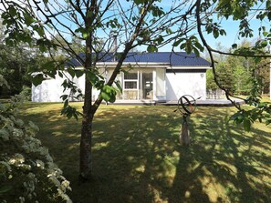 A house with a covered porch, a lawn, and a tree in the foreground. - 4 Star Holiday Home in Hojslev (Hojslev)