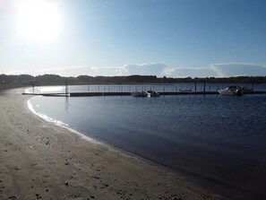 A beach with calm water, a pier, and boats.