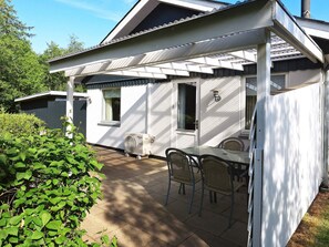 Una casa blanca con un patio techado, una mesa y sillas.