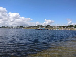 A marina with boats docked, a clear sky, and a calm water body.
