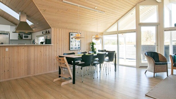 Une cuisine spacieuse aux murs en bois et une grande salle à manger dotée d’un haut plafond.
