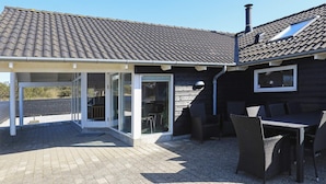 Un patio couvert avec une table et des chaises, une porte-fenêtre coulissante et une cheminée.