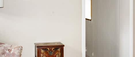 A room with a bed, a small wooden table, and a radiator.