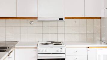Une cuisine avec des meubles blancs, une hotte de cuisine Siemens et une cuisinière Electrolux.