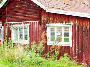 A red wooden building with two windows, surrounded by greenery. - 4 Person Holiday Home in Tallberg (Tallberg)