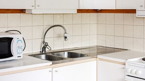 A kitchen with white cabinets, a stainless steel sink, a microwave, and a stove. - 4 Person Holiday Home in Tallberg (Tallberg)