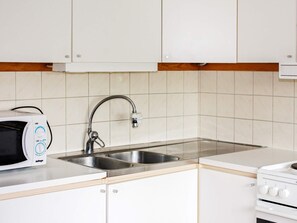 A kitchen with white cabinets, a stainless steel sink, a microwave, and a stove. - 4 Person Holiday Home in Tallberg (Tallberg)