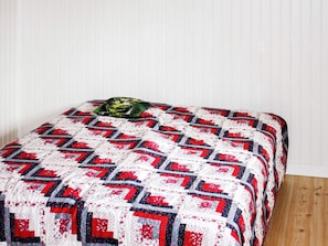 A bed with a quilt featuring a geometric pattern and a pillow with a cat design. - 4 Person Holiday Home in Tallberg (Tallberg)