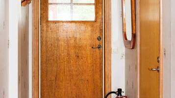 Une porte en bois avec une fenêtre, un extincteur et un miroir accroché au mur.
