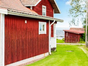 A red wooden house with a white porch and a window.