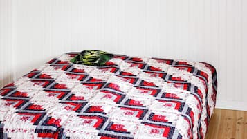 A bed with a patterned quilt, a pillow, and a wooden floor.