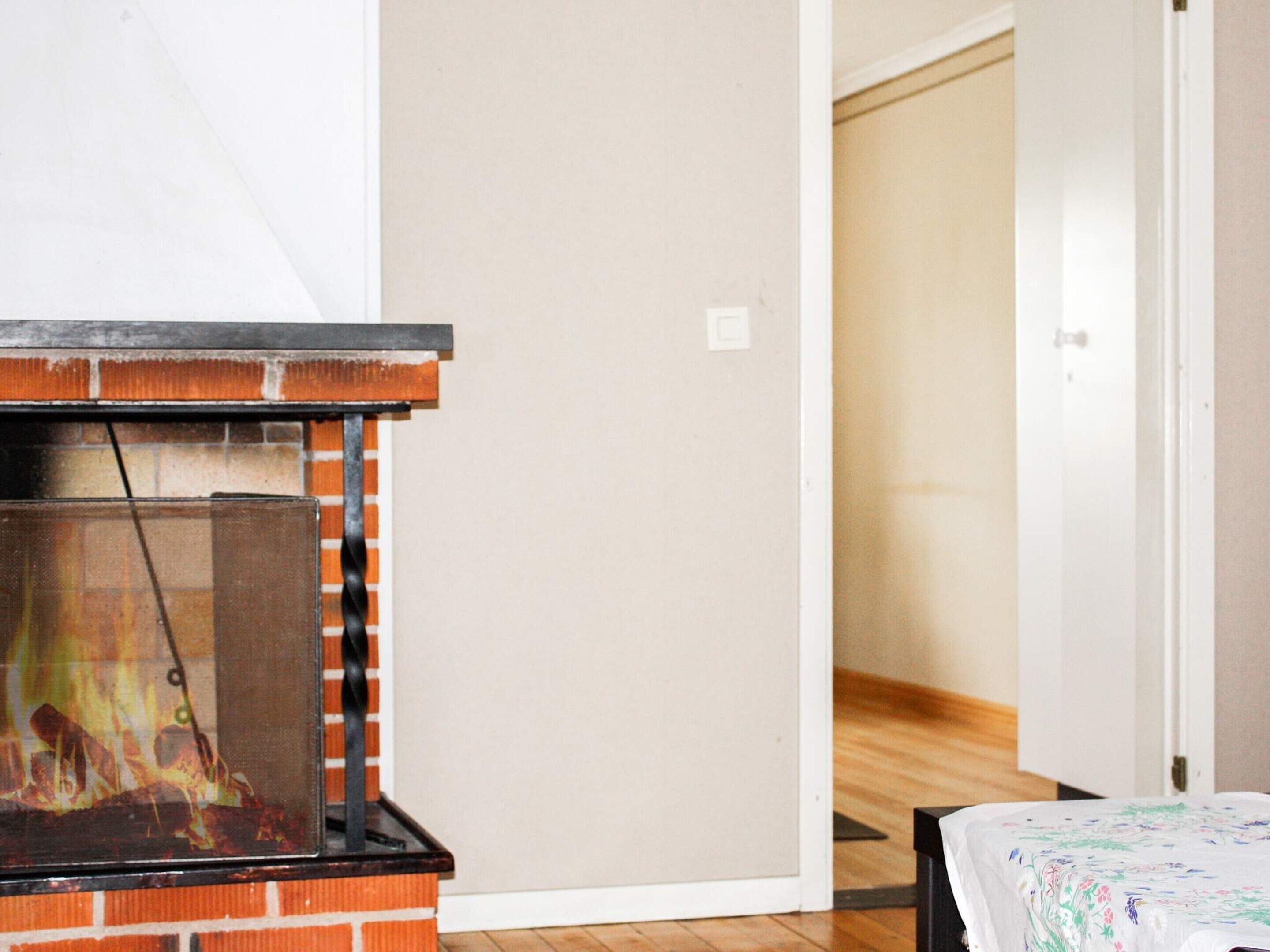 Une pièce avec une cheminée, un lit recouvert d’une couvre-lit à motifs floraux et un plancher en bois.