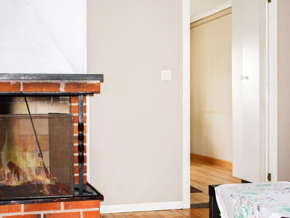 A room with a fireplace, a bed with a floral bedspread, and a wooden floor.