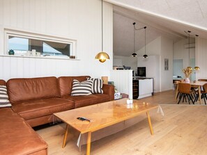 A modern living room with a brown leather sofa, a wooden coffee table, and pendant lighting.