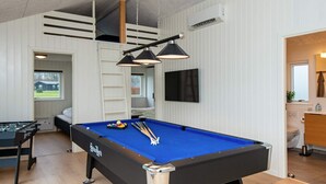 A pool table with a blue felt surface, a foosball table, and a television mounted on the wall. - 5 Star Holiday Home in Sydals (Sydals)