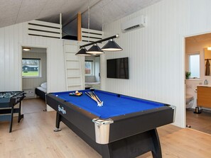 Ein Billardtisch mit blauer Spielvliesbahn, ein Fußballtisch und ein an der Wand befestigter Fernseher.