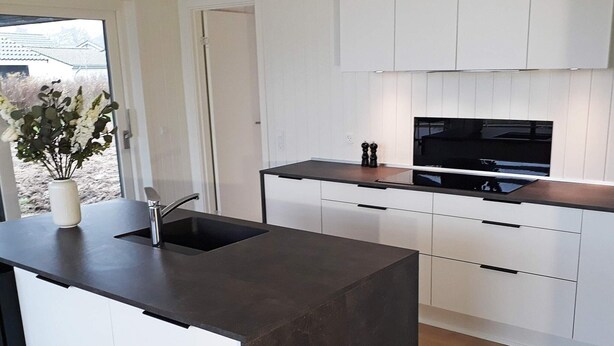 A modern kitchen with a black countertop, white cabinetry, and a built-in oven. - 5 Star Holiday Home in Sydals (Sydals)