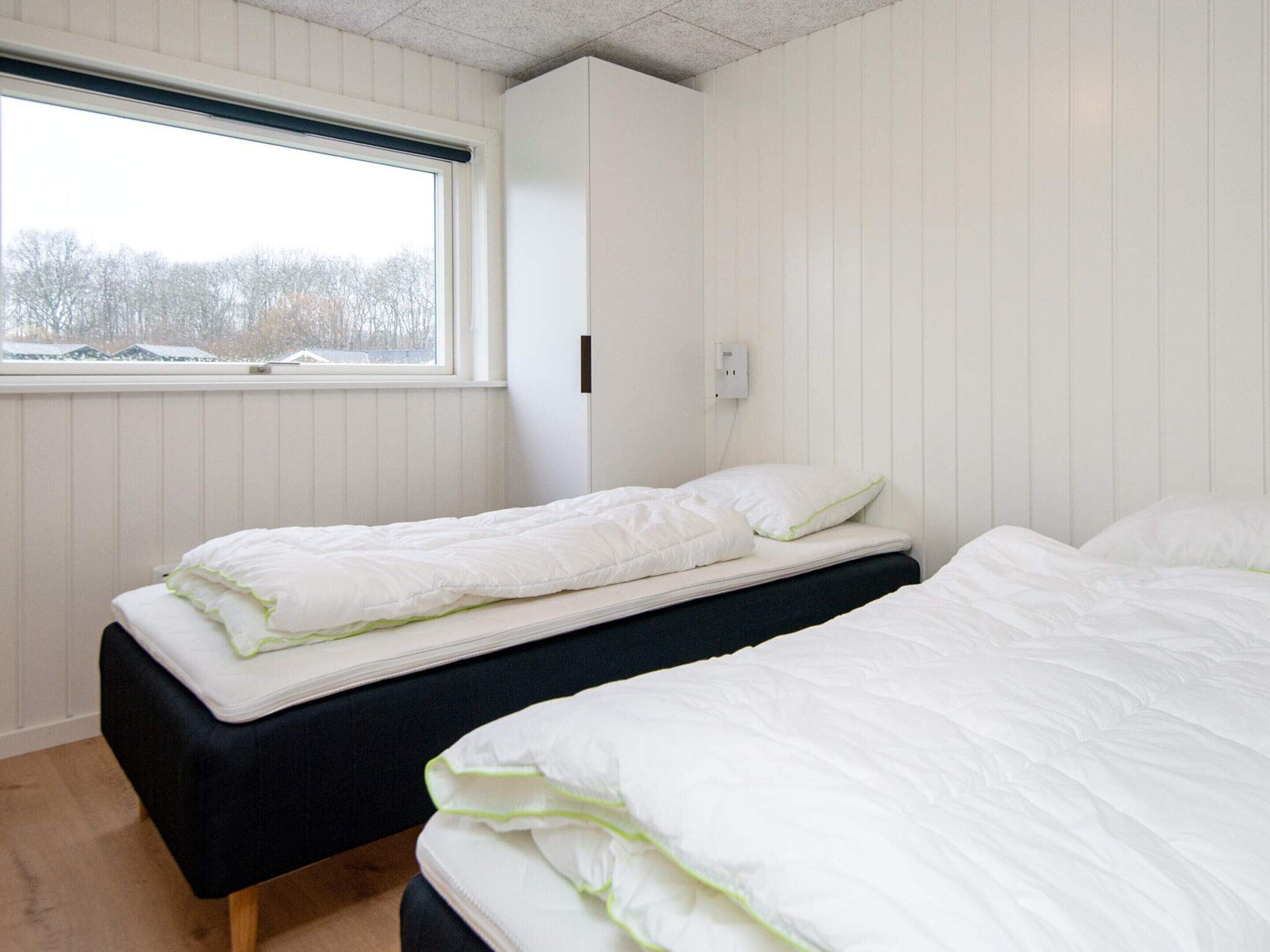A room with two beds, a window, and a white wall.
