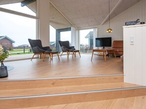 A spacious living area with a large window, a flat-screen TV, and a sofa. - 5 Star Holiday Home in Sydals (Sydals)