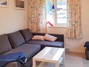 A living room with a grey sofa, a white coffee table, and floral curtains. - 4 Star Holiday Home in Ljusdal (Ljusdal)