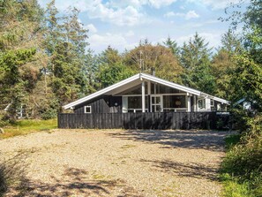 A single-story cabin with a sloped roof, large windows, and a wooden fence. - 4 Star Holiday Home in Blavand (Blavand)