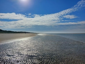 A beach with a clear sky, gentle waves, and distant dunes. - 4 Star Holiday Home in Blavand (Blavand)
