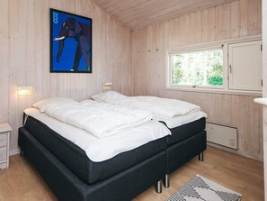 Quarto com duas camas, paredes de madeira, uma janela e um quadro.