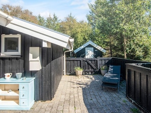 A wooden cottage with a brick patio, a small shed, and a blue bench. - 4 Star Holiday Home in Blavand (Blavand)