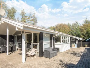 A covered outdoor area with a patio, seating, and a view of the surrounding trees. - 4 Star Holiday Home in Blavand (Blavand)