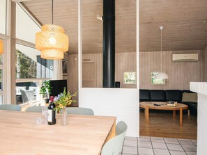 Interior moderno com área de jantar, sofá preto e uma janela grande.