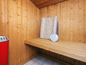 A wooden sauna room with a bench, a towel, and a thermometer. - 4 Star Holiday Home in Blavand (Blavand)