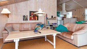 A cozy living room with a wooden wall, a sofa, a table, and a kitchen area in the background. - 6 Person Holiday Home in Fano-by Traum (Fano)