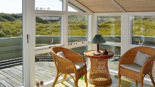 A covered balcony with wicker chairs, a small table, and a view of the landscape. - 6 Person Holiday Home in Fano-by Traum (Fano)
