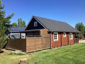 A log cabin with a sloped roof, solar panels, and a wooden fence.