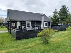 A log cabin with a deck, outdoor seating, and a large window.