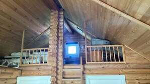 A cabin interior with a loft bedroom, wooden log walls, and a window providing natural light. - 6 Person Holiday Home in Hovborg (Hovborg)