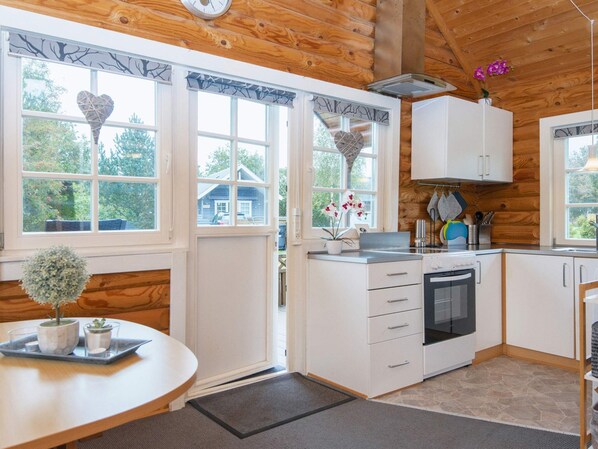 A kitchen with white cabinets, a stove, and a window with a view of a house.