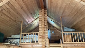 A wooden attic room with a sloped ceiling, wooden railings, and a loft bed with bedding. - 6 Person Holiday Home in Hovborg (Hovborg)