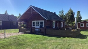 A log cabin with a pitched roof, a deck, and a fenced yard. - 6 Person Holiday Home in Hovborg (Hovborg)
